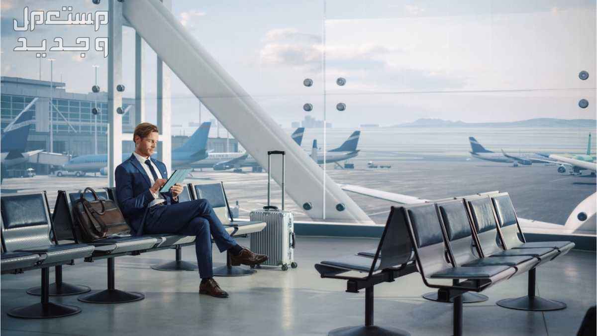 موقع رحلات موثوق لحجز تذاكر الطيران رجل يرتدي بدلة وفي يده ايباد ويجلس في ساحة انتظار المطار