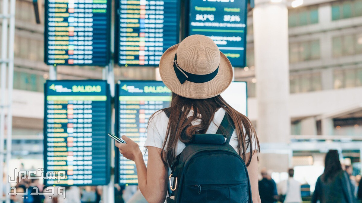 تقسيط تذكرة السفر عبر خدمة تذاكر طيران تمارا امراة ترتدي قبعة تنظر الى مواعيد الرحلات في المطار