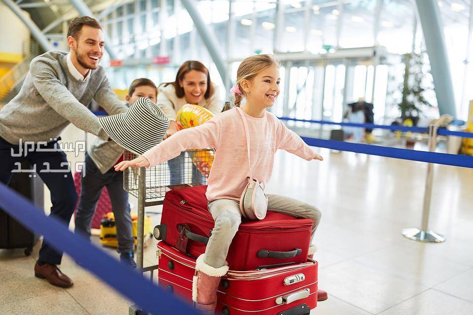 ما هو أرخص شهر لتذاكر الطيران وحجوزات السفر والرحلات؟ طفلة تجلس على حقائب السفر مبتهجة