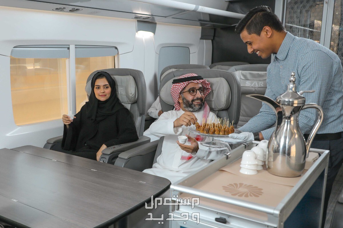 جدول رحلات قطار سار القصيم الرياض وأسعار التذاكر في السعودية موظف يقوم بتقديم القهوة لرجل وزوجته في قطار سار