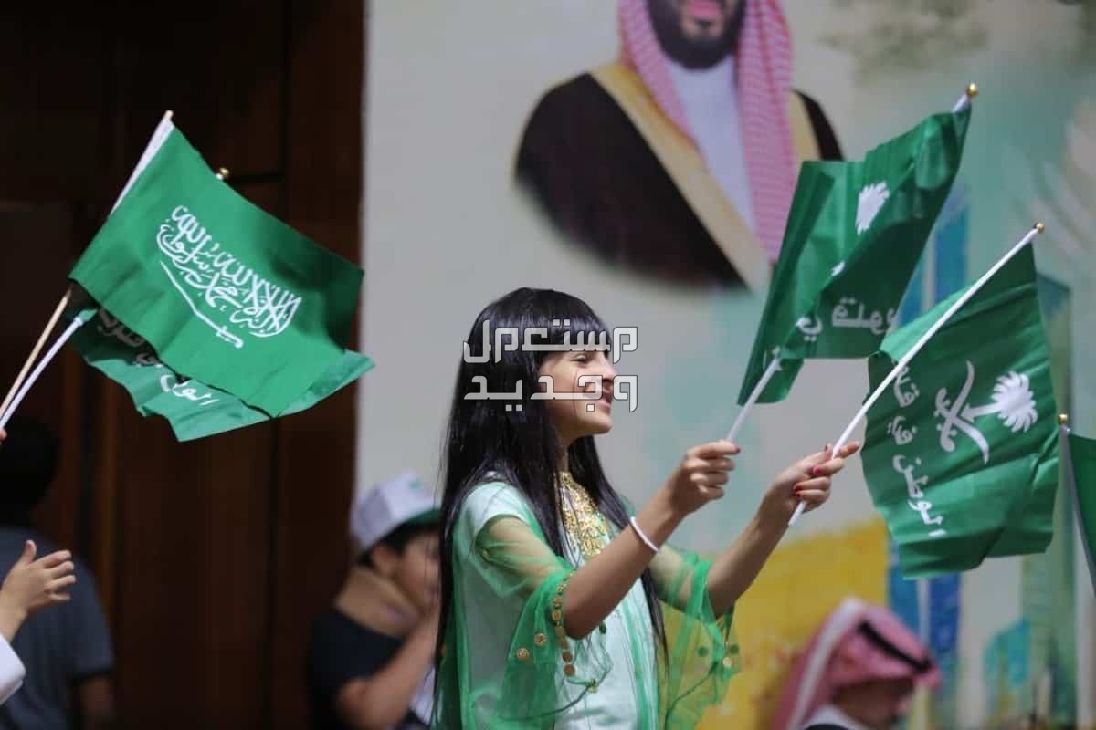 أبرز مظاهر الاحتفال باليوم الوطني السعودي فتاة تحمل أعلام خضراء للمملكة