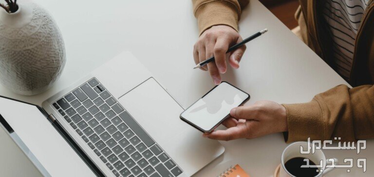 خطوات وشروط فتح متجر إلكتروني في السعودية رجل يستخدم الهاتف الجوال واللاب توب