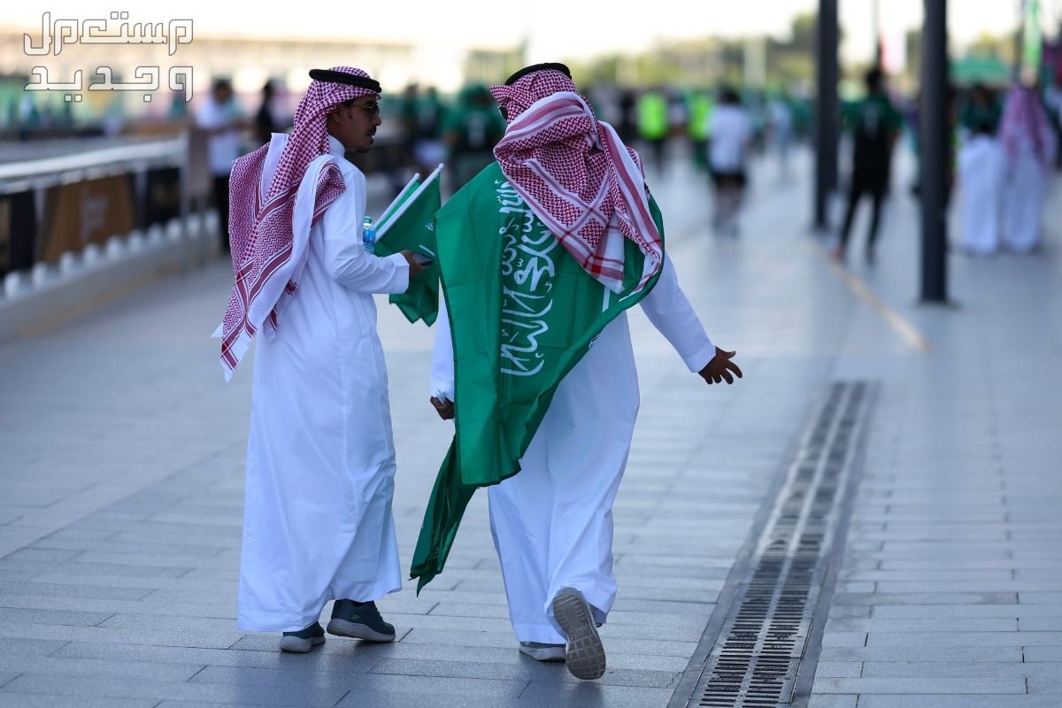 جميع العطلات الرسمية في السعودية 1446 رجلان يحملان العلم السعودي