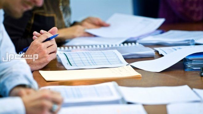 ما هو نظام السجل التجاري الجديد في السعودية؟ الشروط والتكاليف مجموعة من الموظفين يتفحصون اوراق هامة
