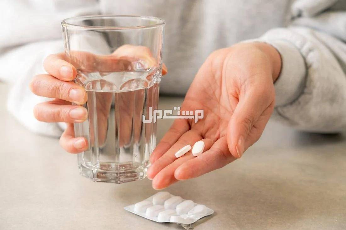 مخاطر تناول الكثير من الباراسيتامول كوب ماء وشريط من الباراسيتامول وجرعة في يد امراة