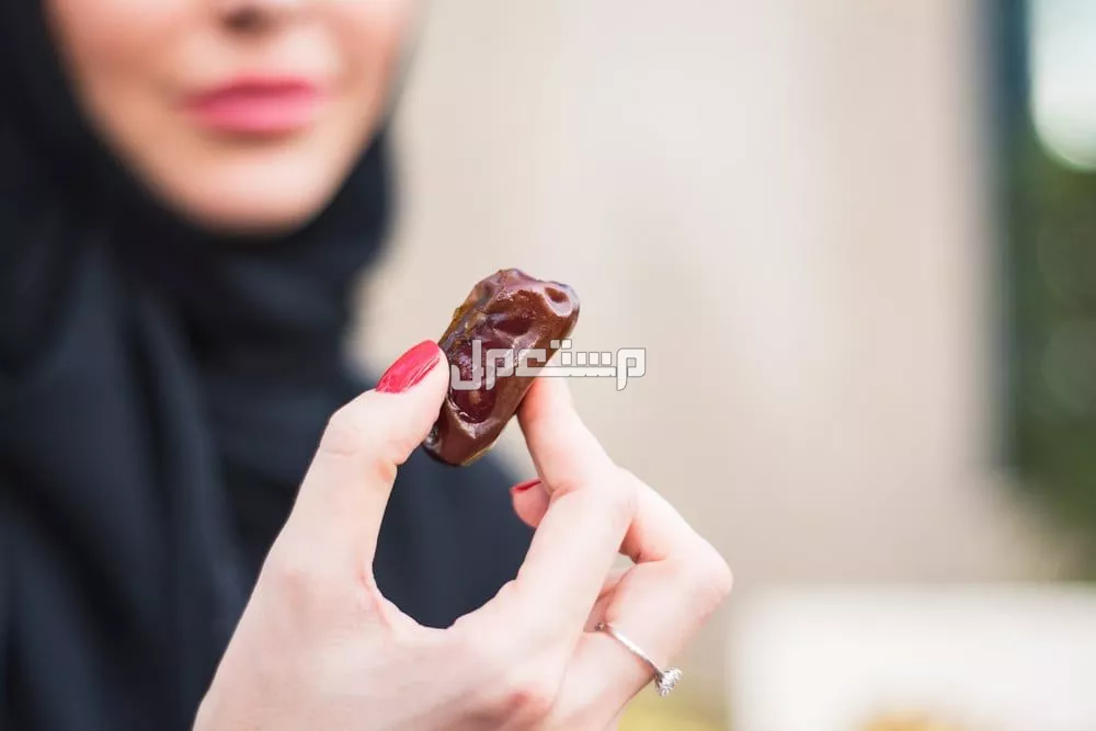 10 فوائد لتناول التمر في فصل الشتاء.. دليل شامل لصحة أفضل سيدة تمسك تمرة في يدها
