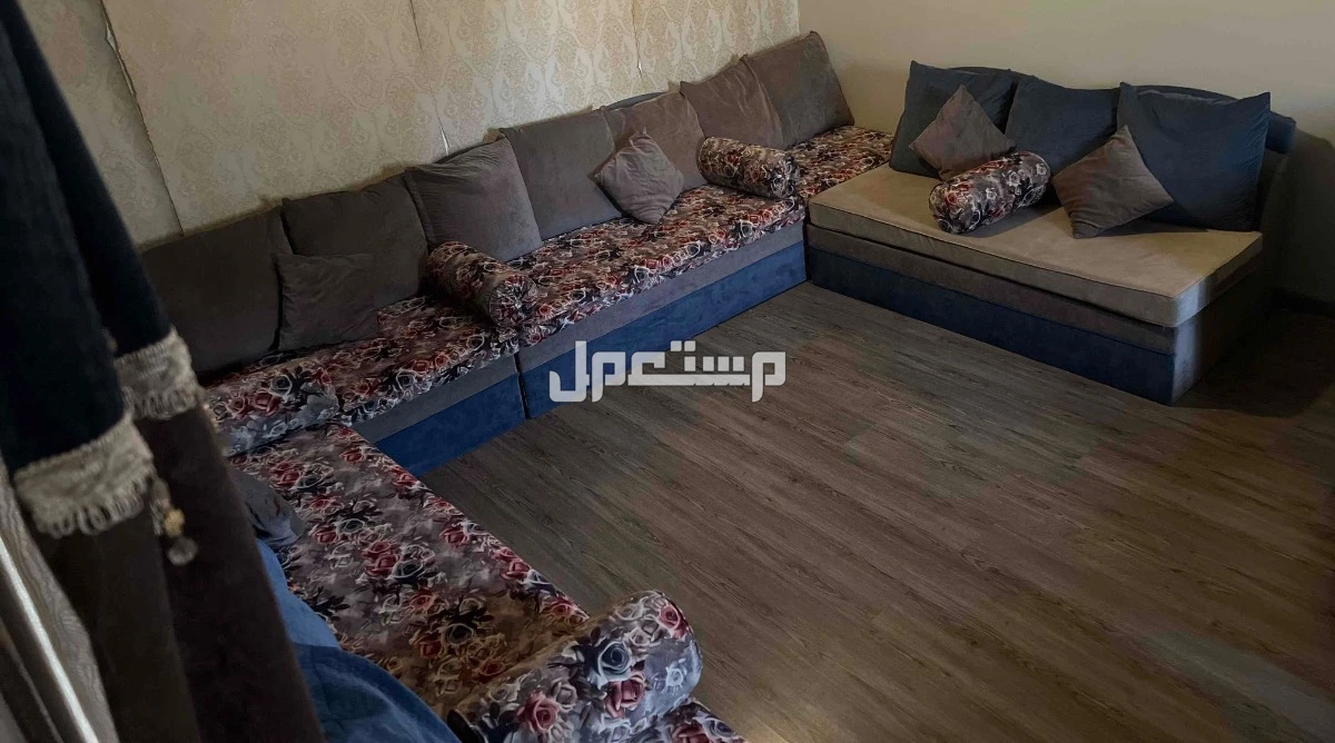كنب ازرق ورمادي ومورد على شكل حرف L مع جهه زياده لثلاث اشخاص